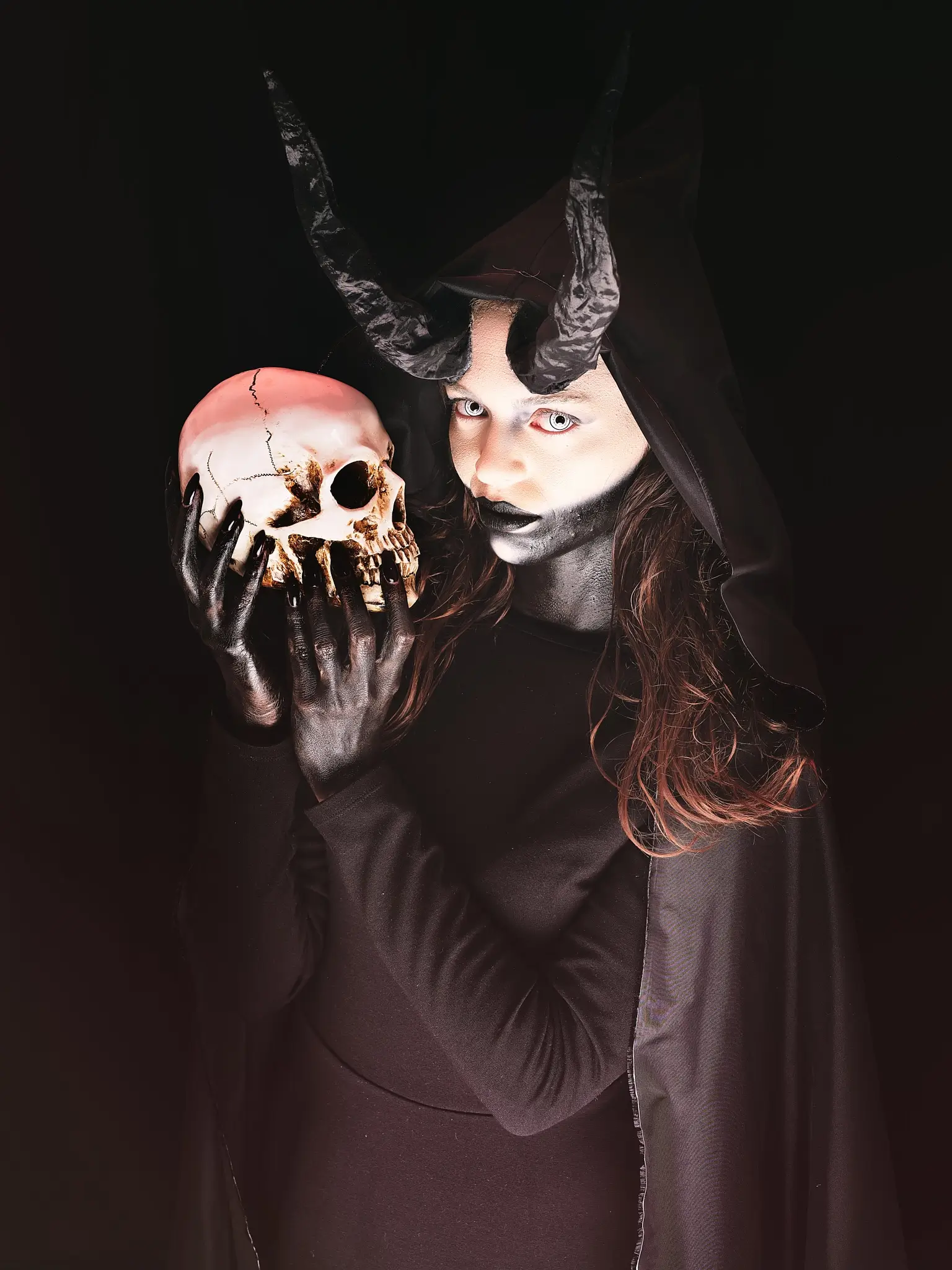 Studio portrait of a model dressed as a creepy monster holding a skull