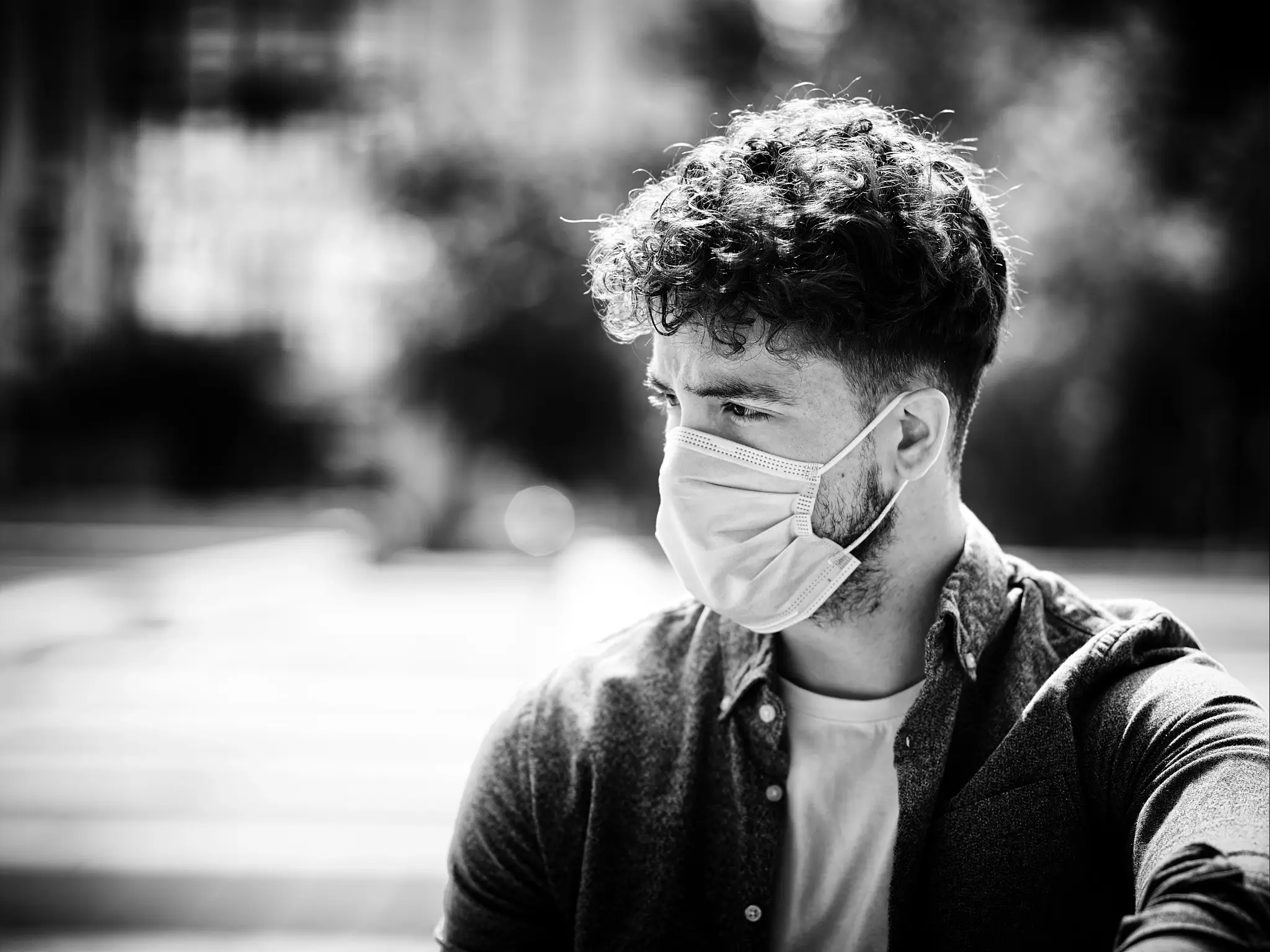 Black and white ortrait of male model wearing a mask. Taken during COVID pandemic