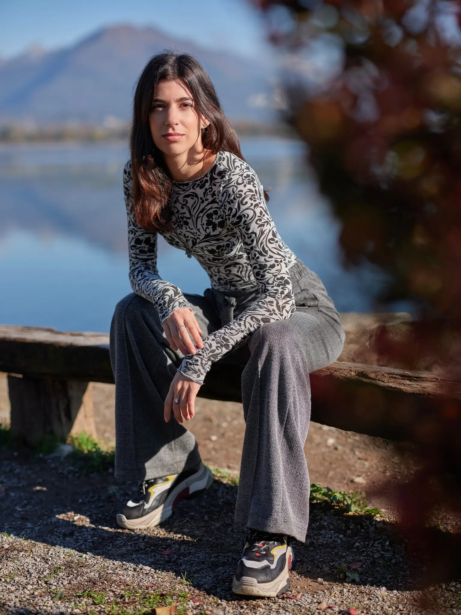 Giada sitting on a wooden bench with the lake in the background, outdoor portrait.