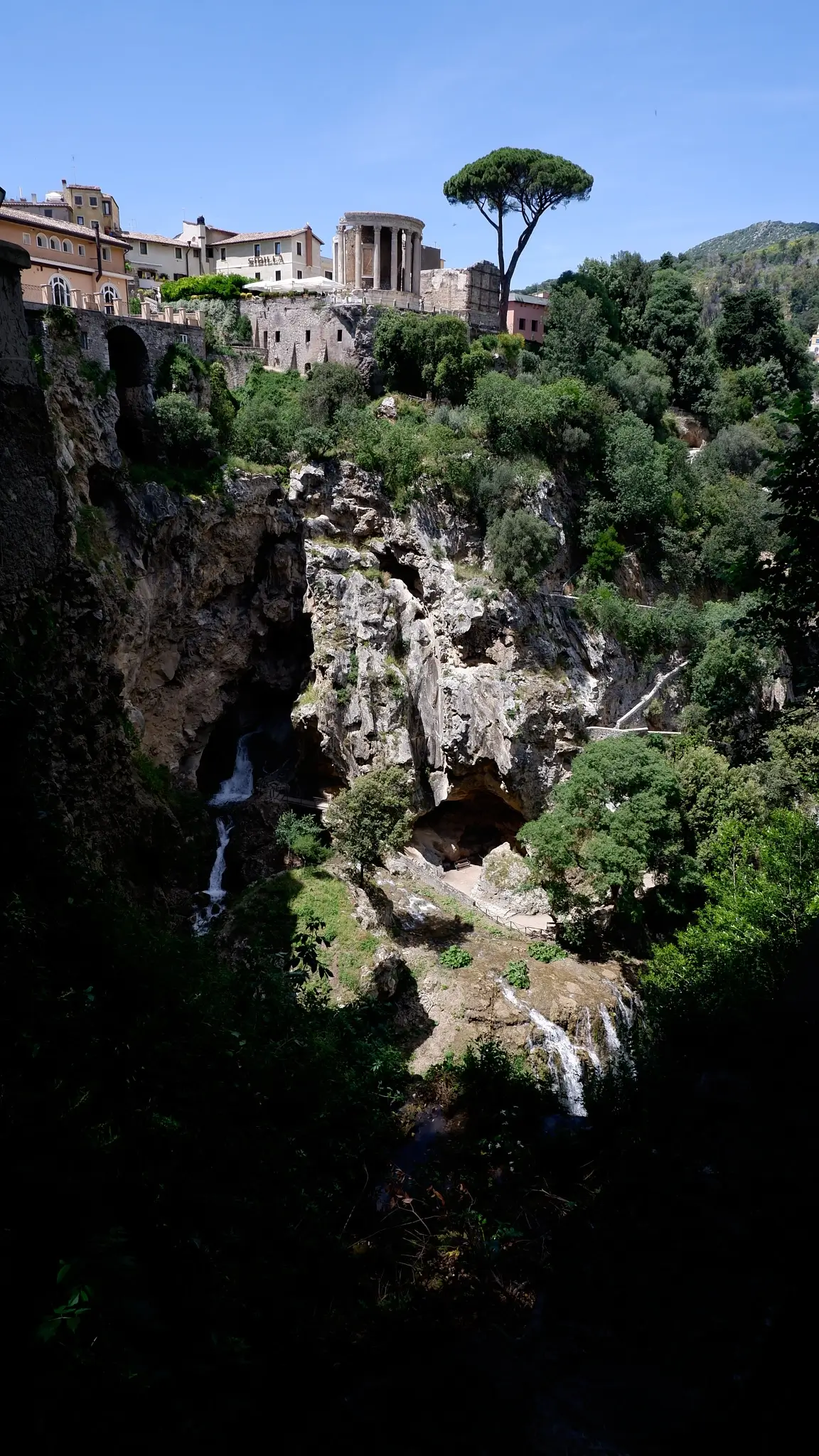 Panoramic view of cliffs, ruins, and waterfall in Tivoli