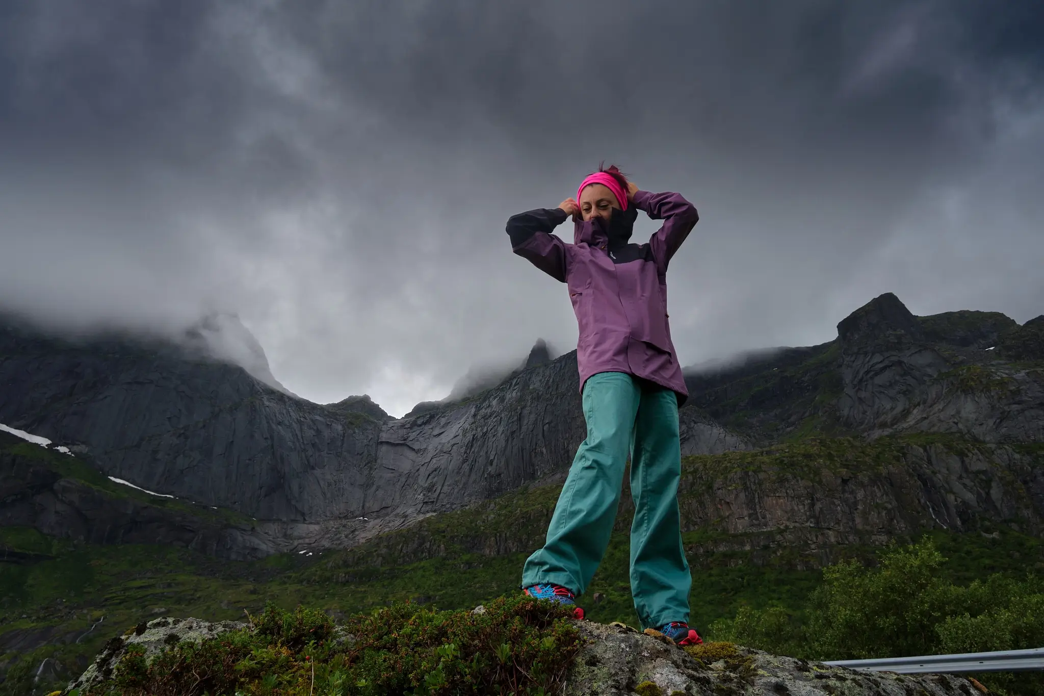 Heavy Arctic clouds over Tamara's head as she climbs black cliffs 