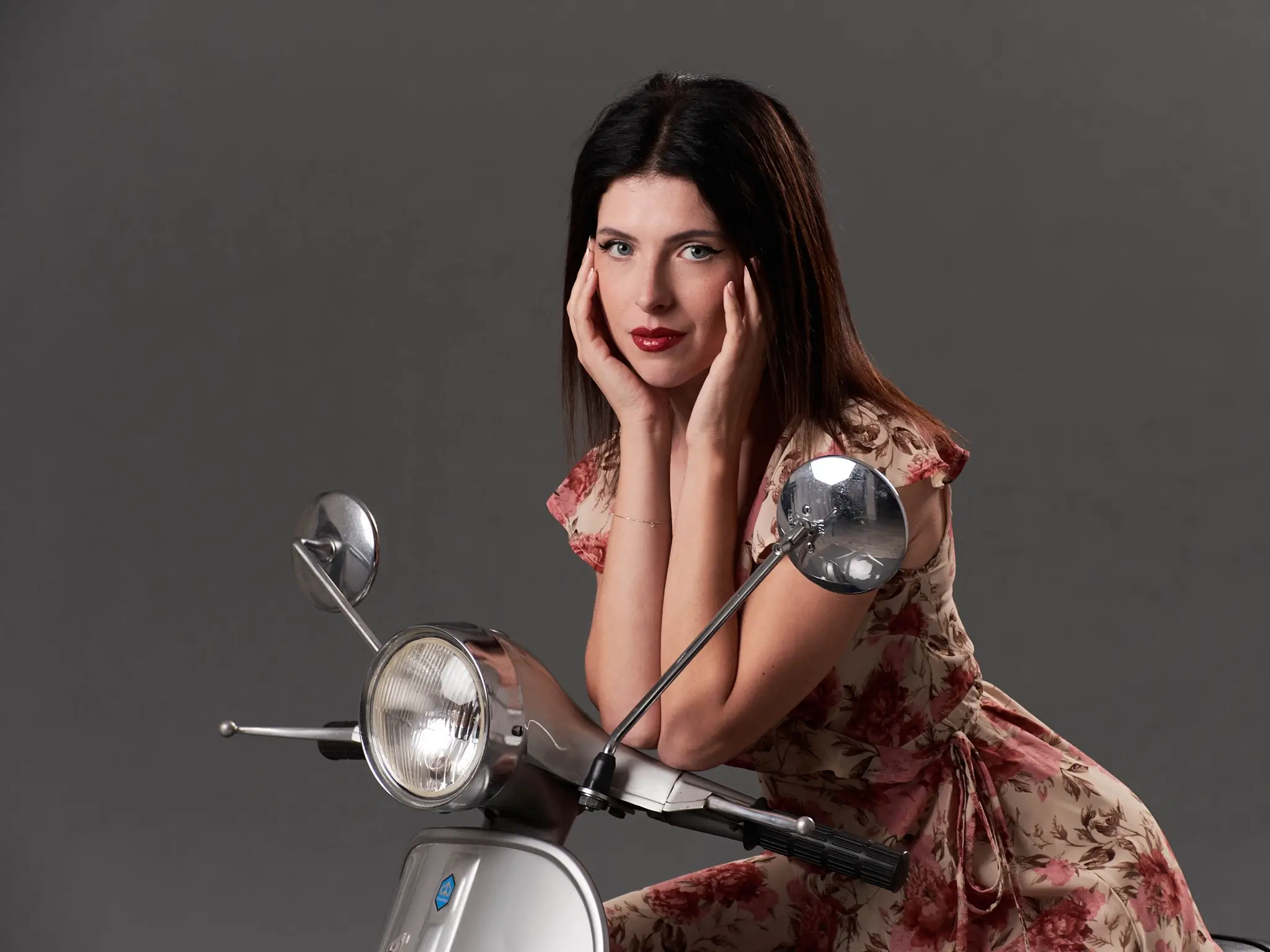 Closeup shot of model Martina wearing a colored dress and sitting on a vintage Vespa during a workshop