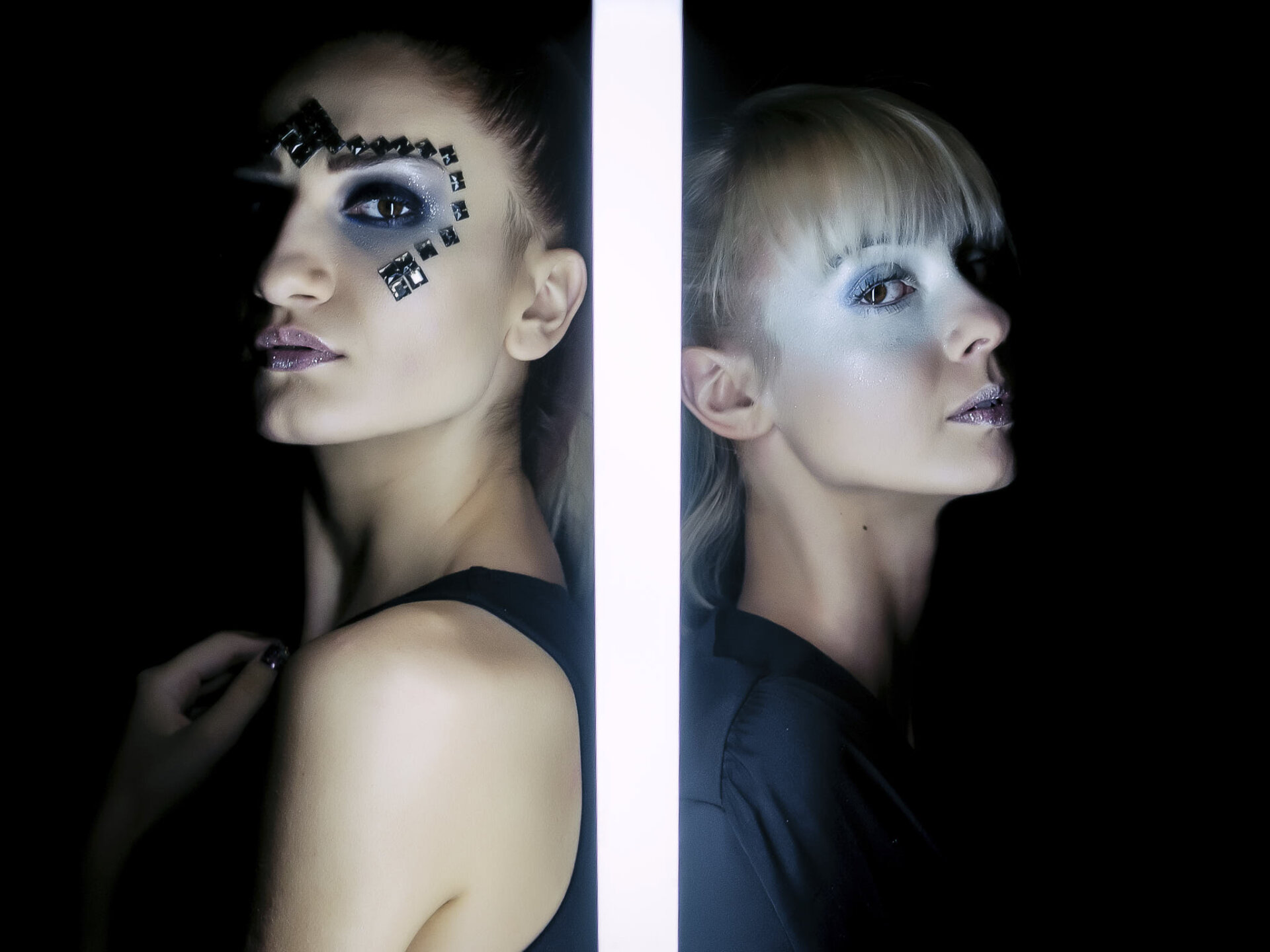 Ritratto di due modelle con makeup futuristico e luce a tubo neon Ritratto di due modelle con make-up futuristico e luce a tubo neon