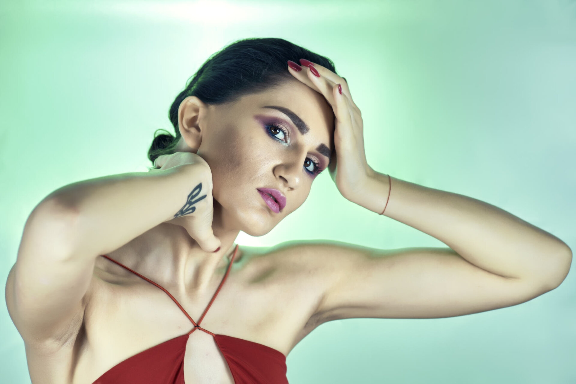 Ritratto beauty di modella con makeup blu e viola e fondale verde