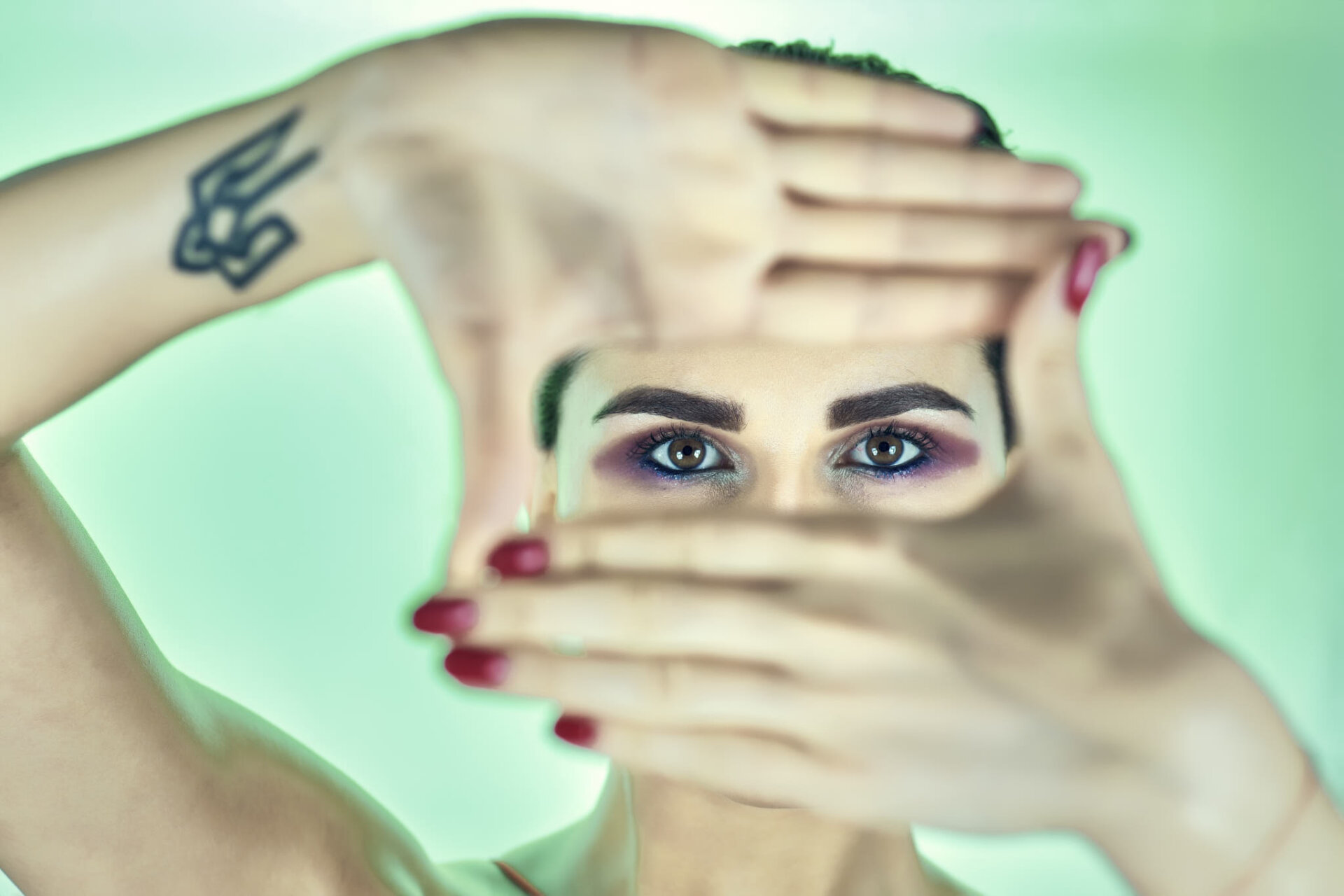 Ritratto beauty di modella con makeup blu e viola e fondale verde