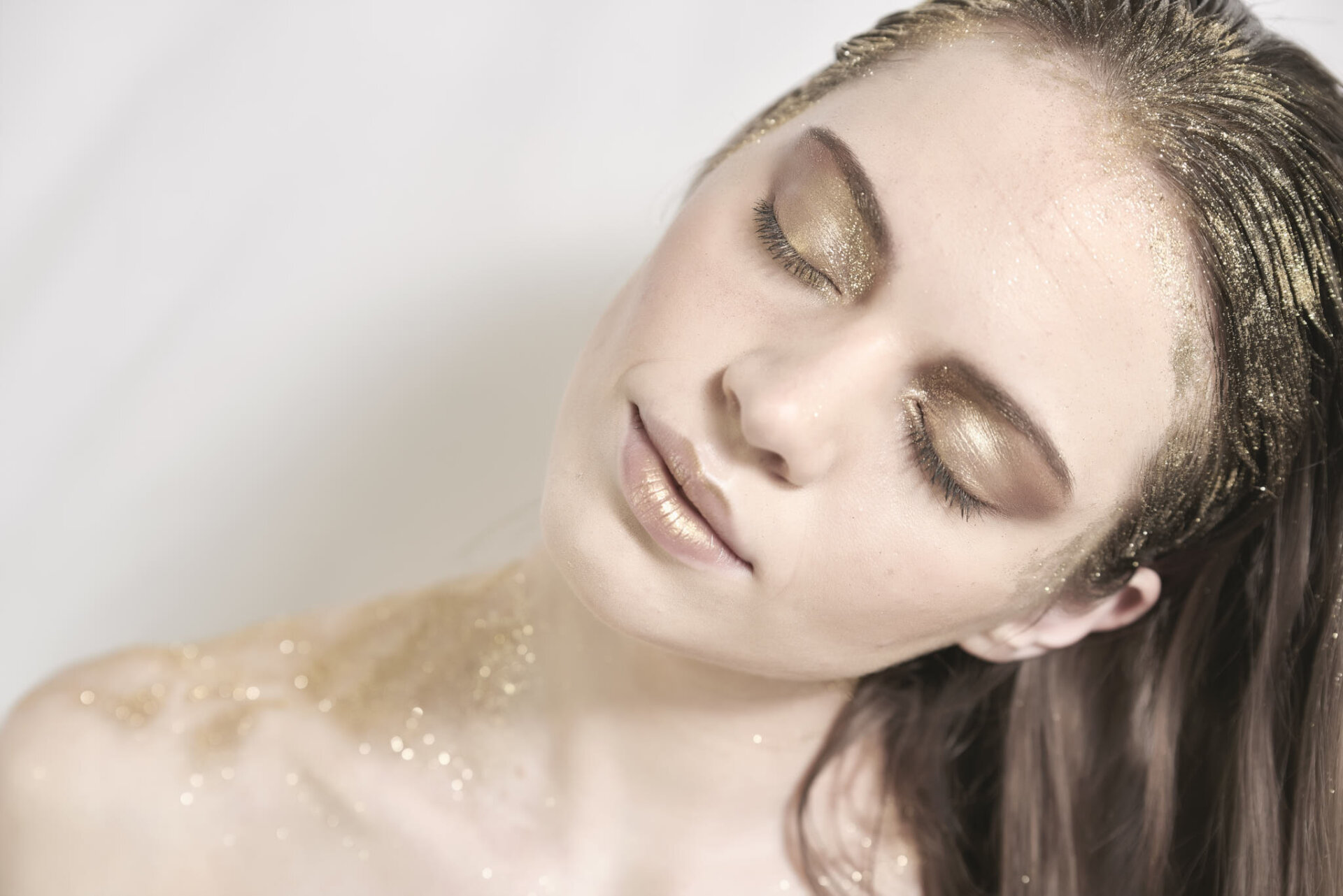 Ritratto beauty di modella con makeup in glitter oro