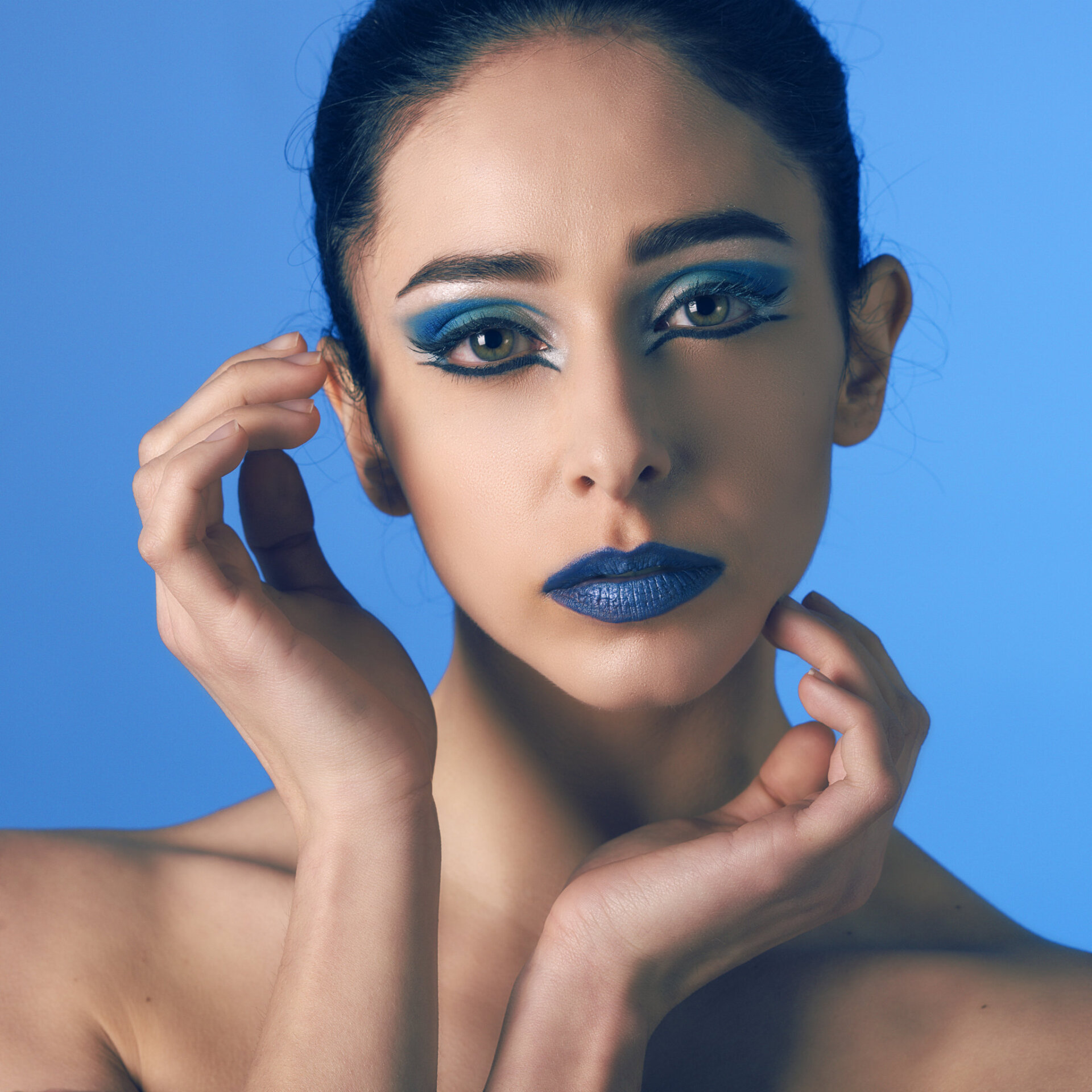 Ritratto beauty di modella con makeup blu e fondale blu